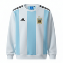 Offizielles Argentinien Sweatshirt 25/26 in Blau und Weiß, Ansicht von vorne. Detailaufnahme des Argentinien-Verbandswappens auf dem Sweatshirt 25/26. Rückansicht des Argentinien Sweatshirts 25/26 für Herren.