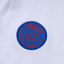 Detailaufnahme des PSG Vereinswappens auf der weißen Trainingsjacke 25/26.